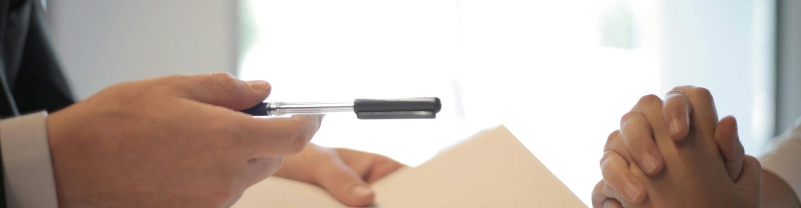 Close-up of a contract signing with hands over documents. Professional business interaction.